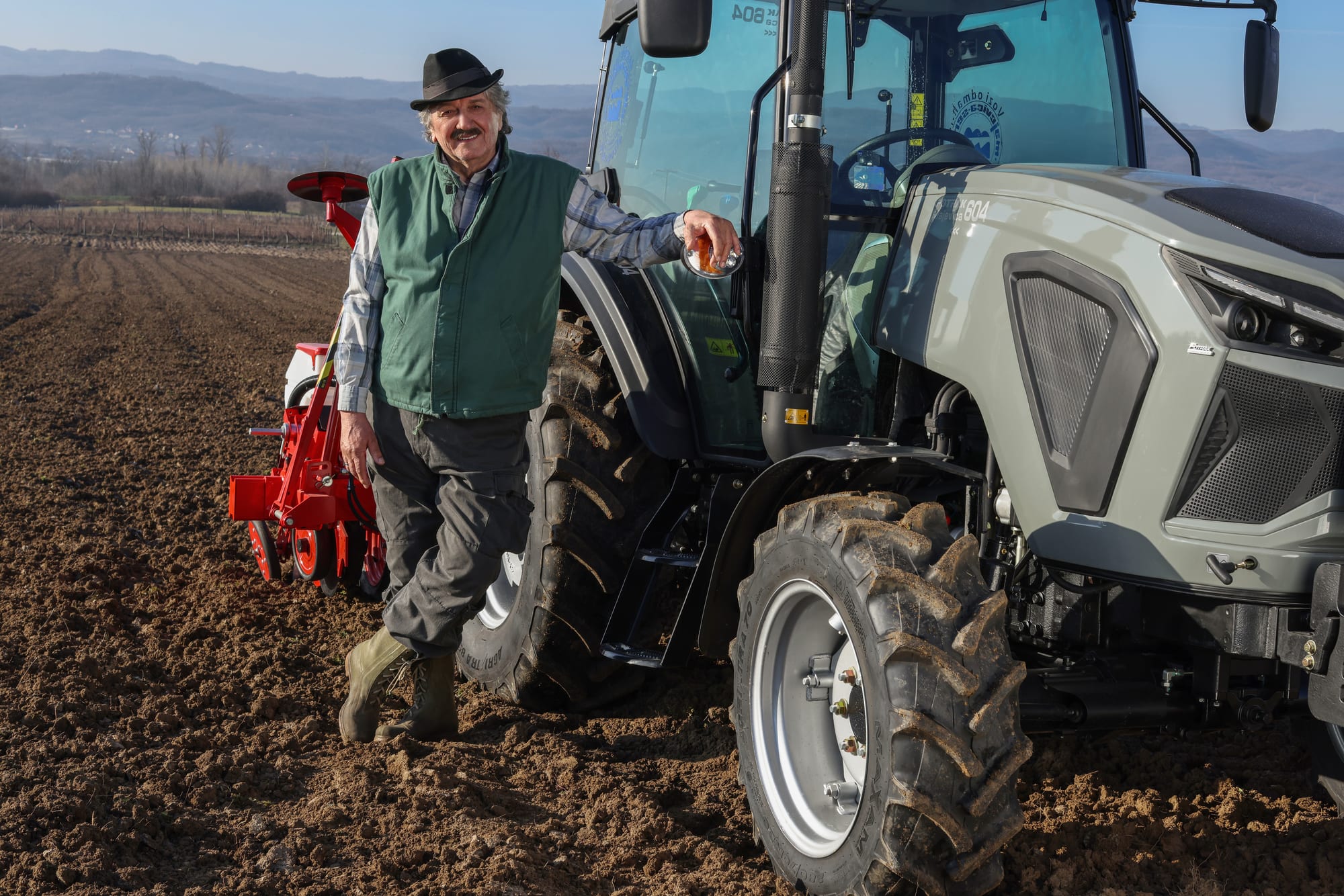 Farmer with a tractor and mounted implement in the field